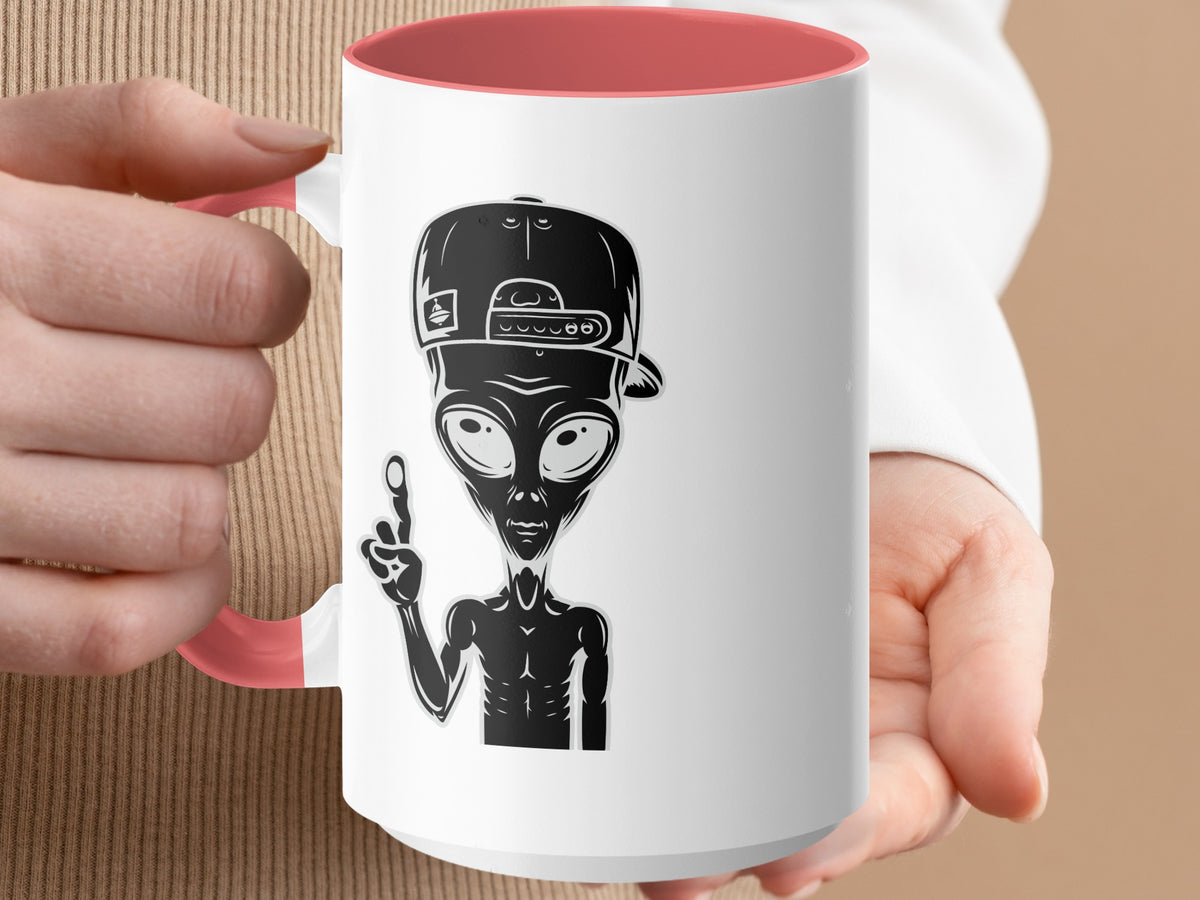 White mug with coral interior, featuring a black alien graphic in a baseball cap.