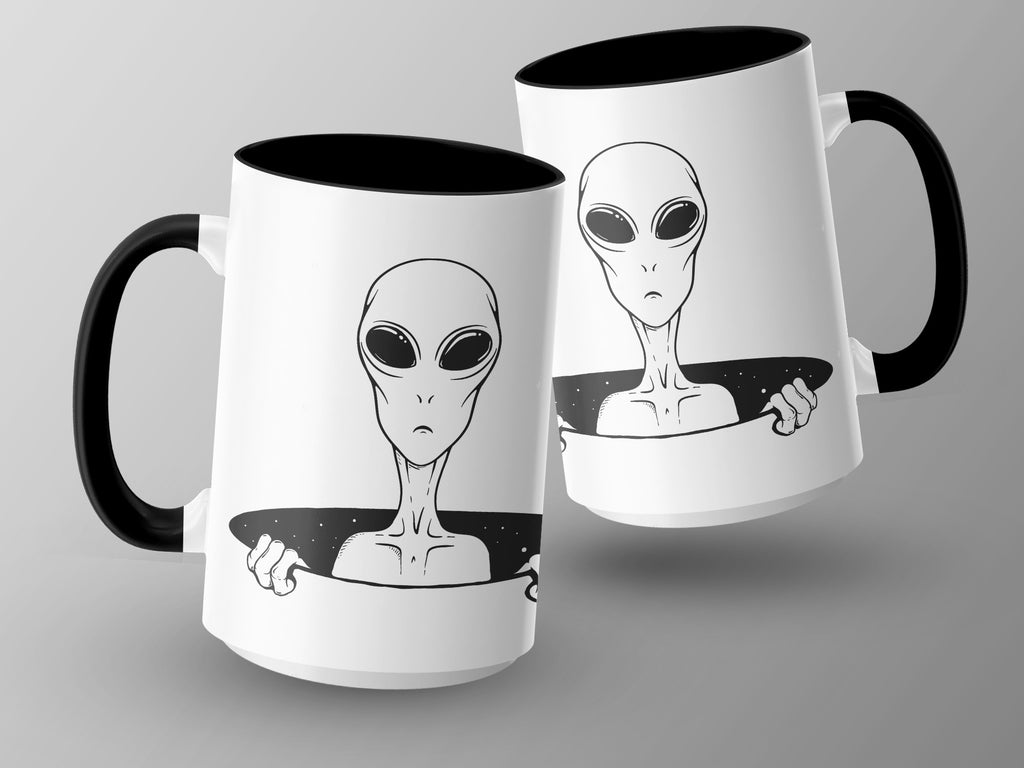 Two white mugs with black handles, each featuring a black line drawing of an alien.