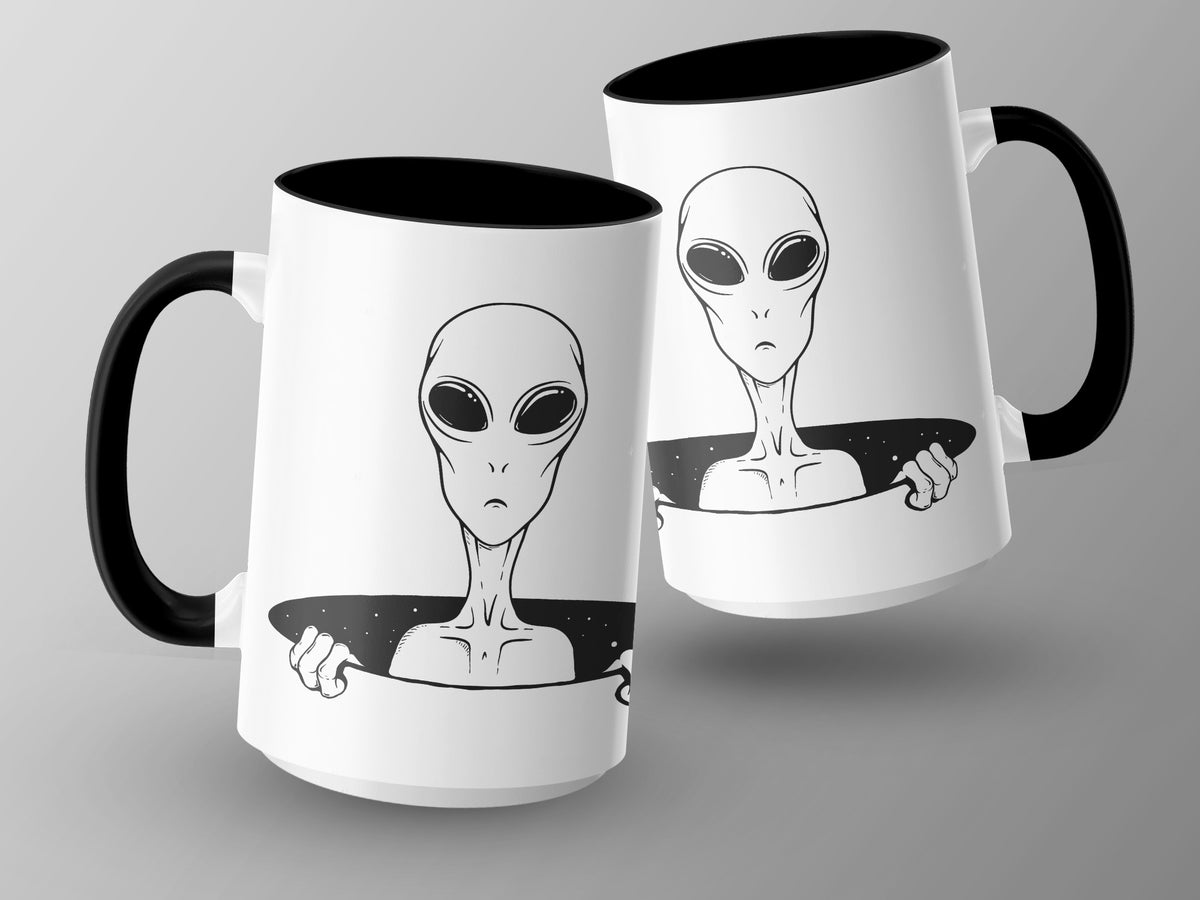 Two white mugs with black handles, each featuring a black line drawing of an alien.