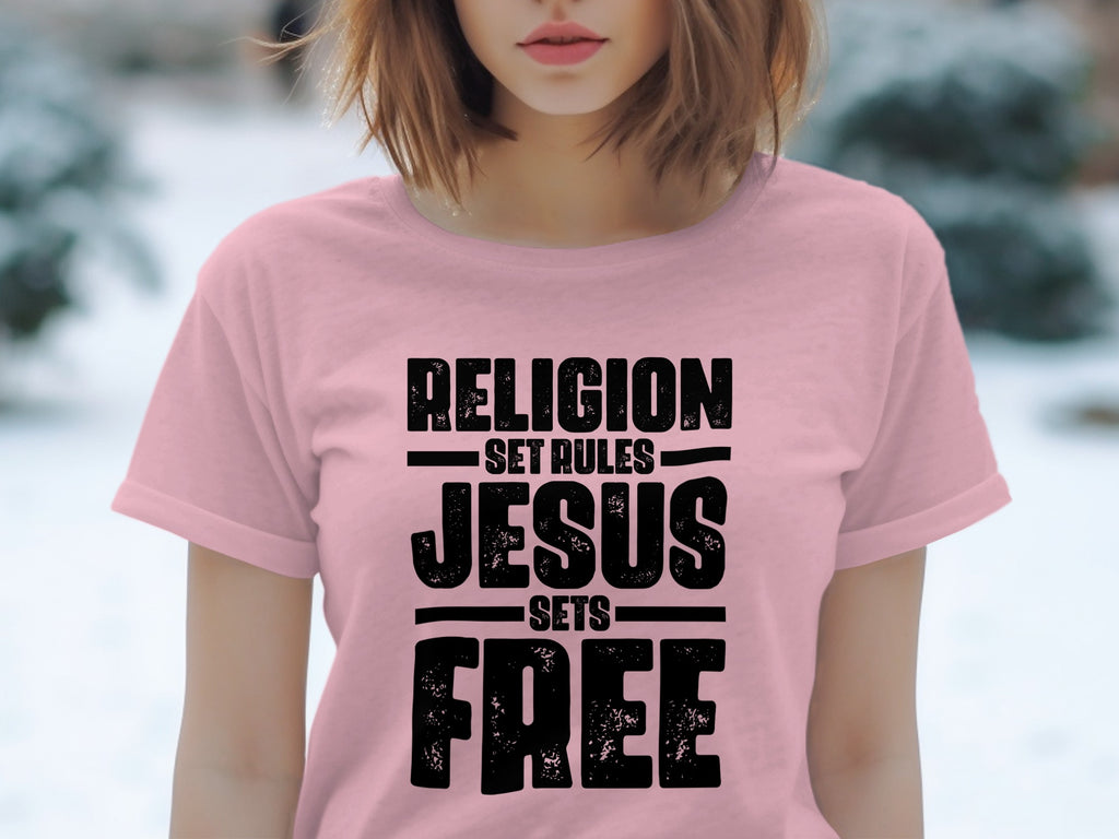 Pink t-shirt with black text "RELIGION SET RULES JESUS SETS FREE"