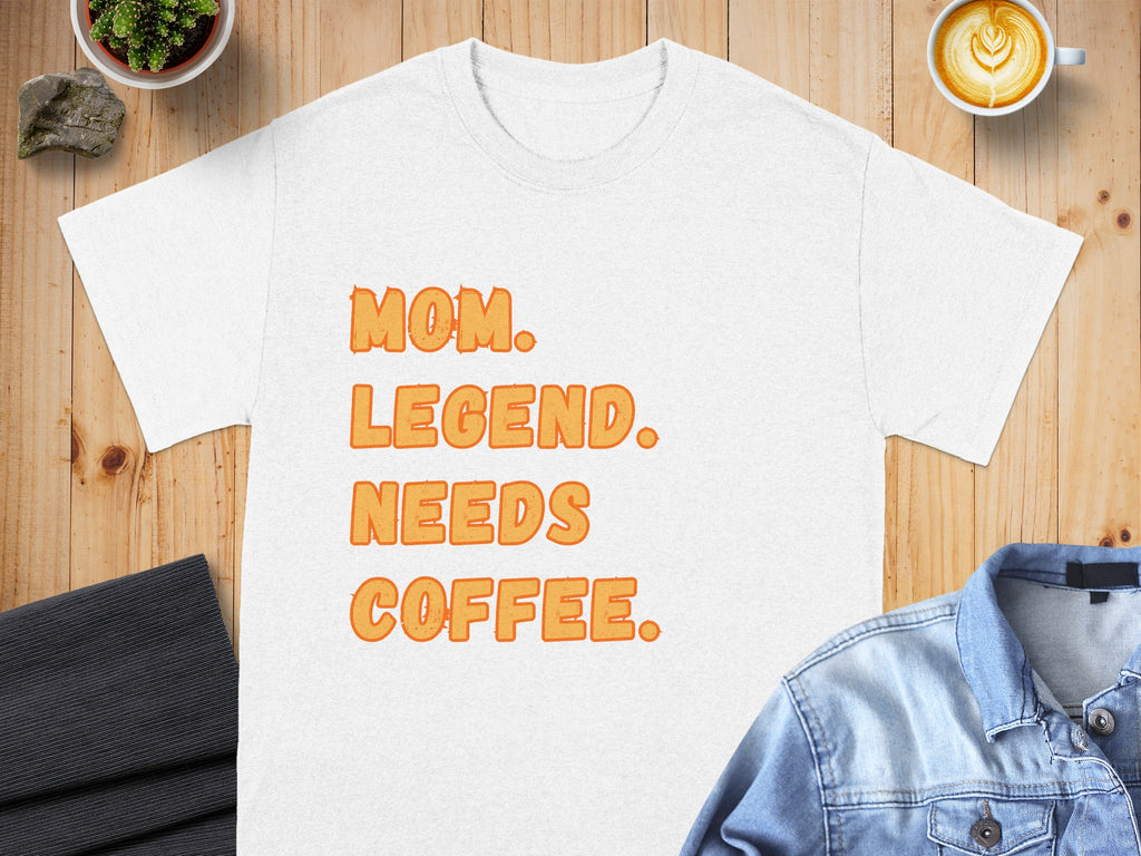 White t-shirt with orange text reading "MOM. LEGEND. NEEDS COFFEE."