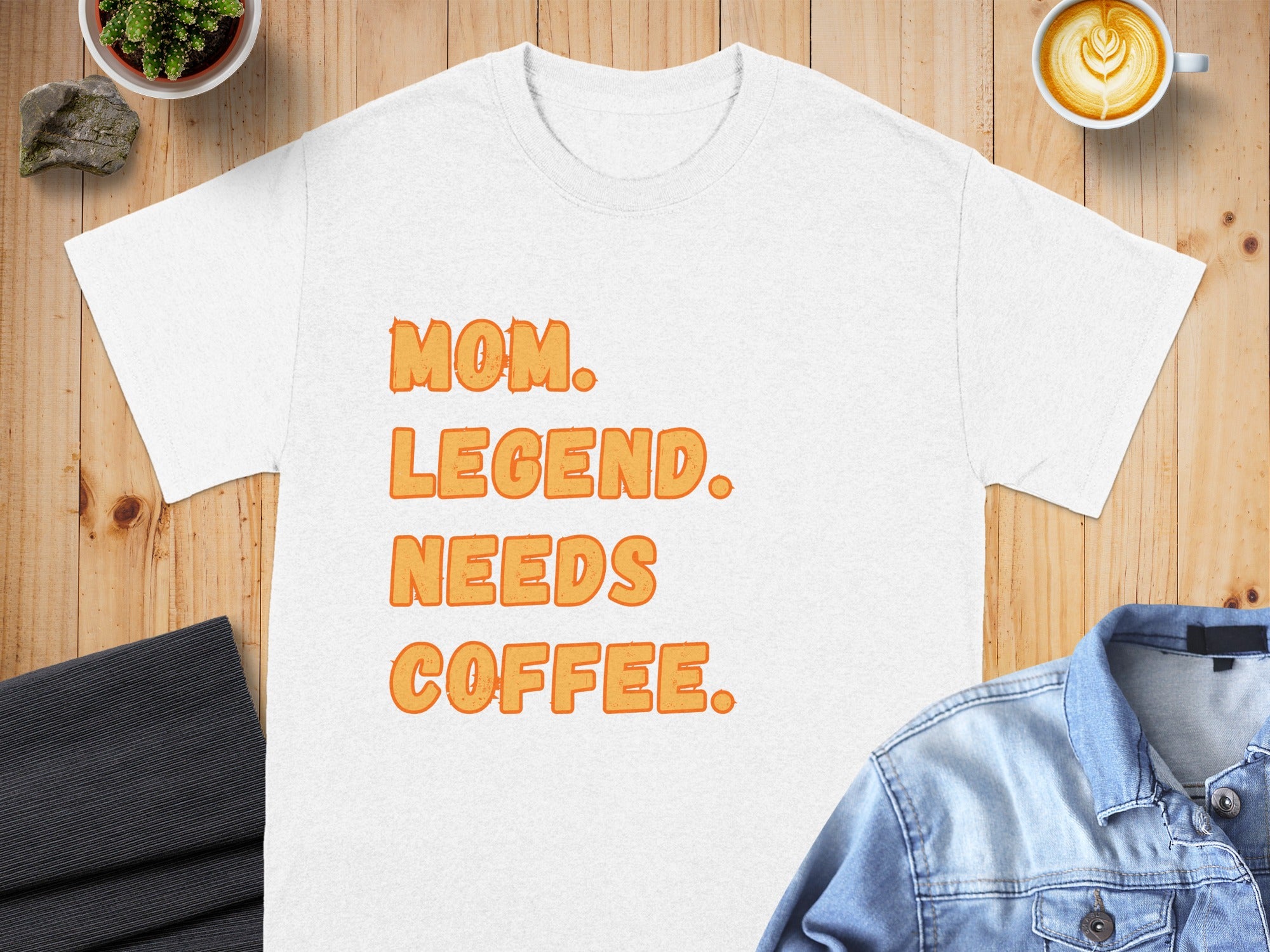 White t-shirt with orange text reading "MOM. LEGEND. NEEDS COFFEE."