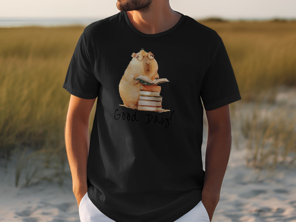 Black t-shirt with watercolor capybara wearing glasses, reading on a stack of books.
