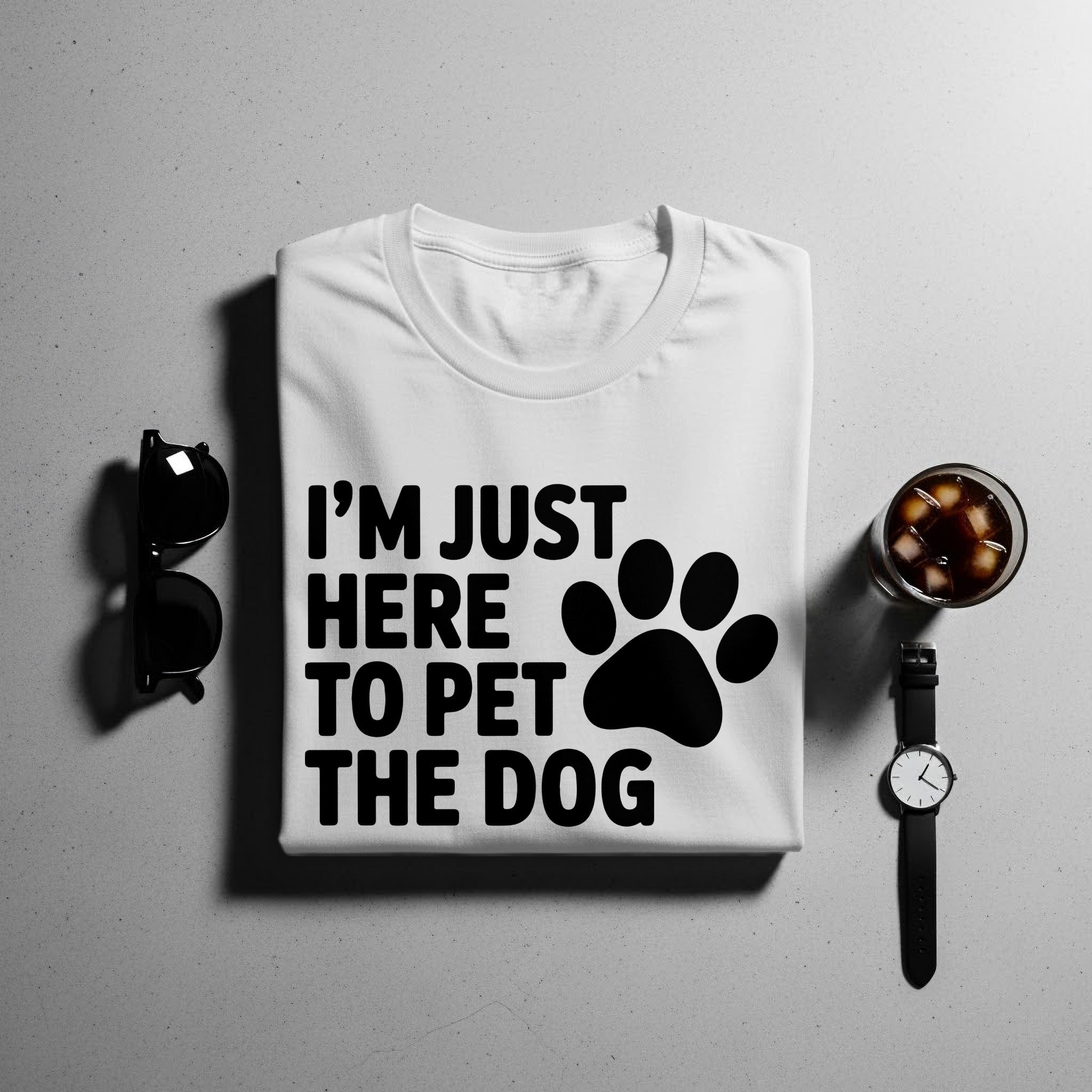 White t-shirt with black text "I'M JUST HERE TO PET THE DOG" and paw print.