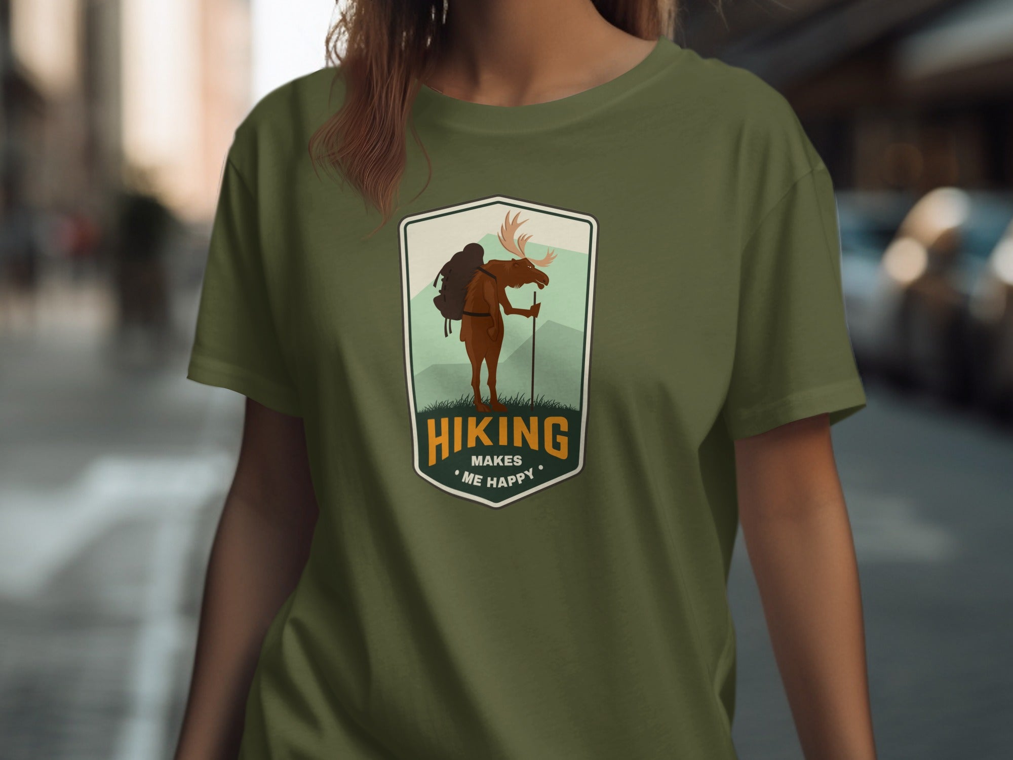 Olive green t-shirt with hiking moose graphic and text "Hiking Makes Me Happy".