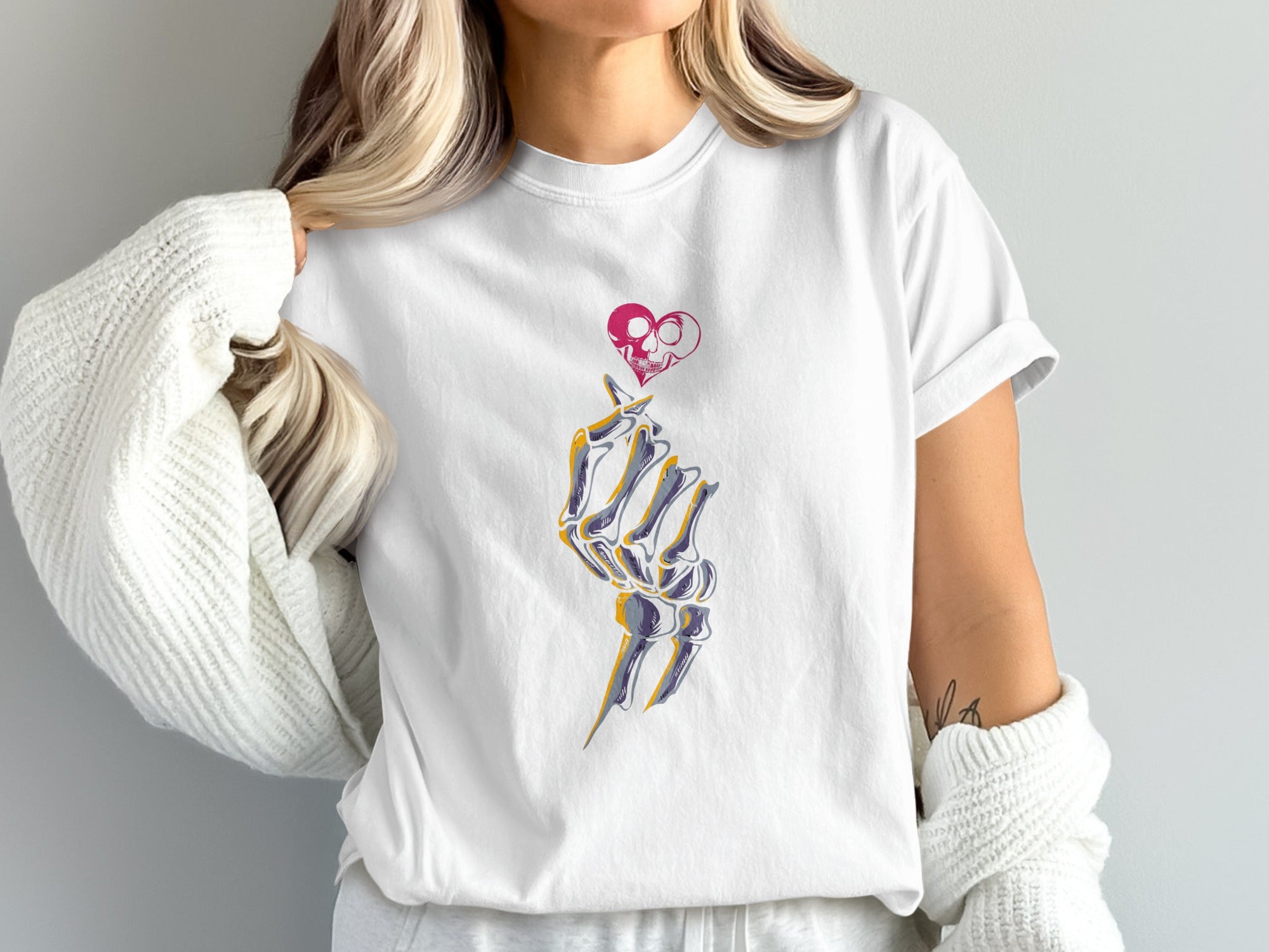 White t-shirt with skeleton hand forming a heart with a skull inside.