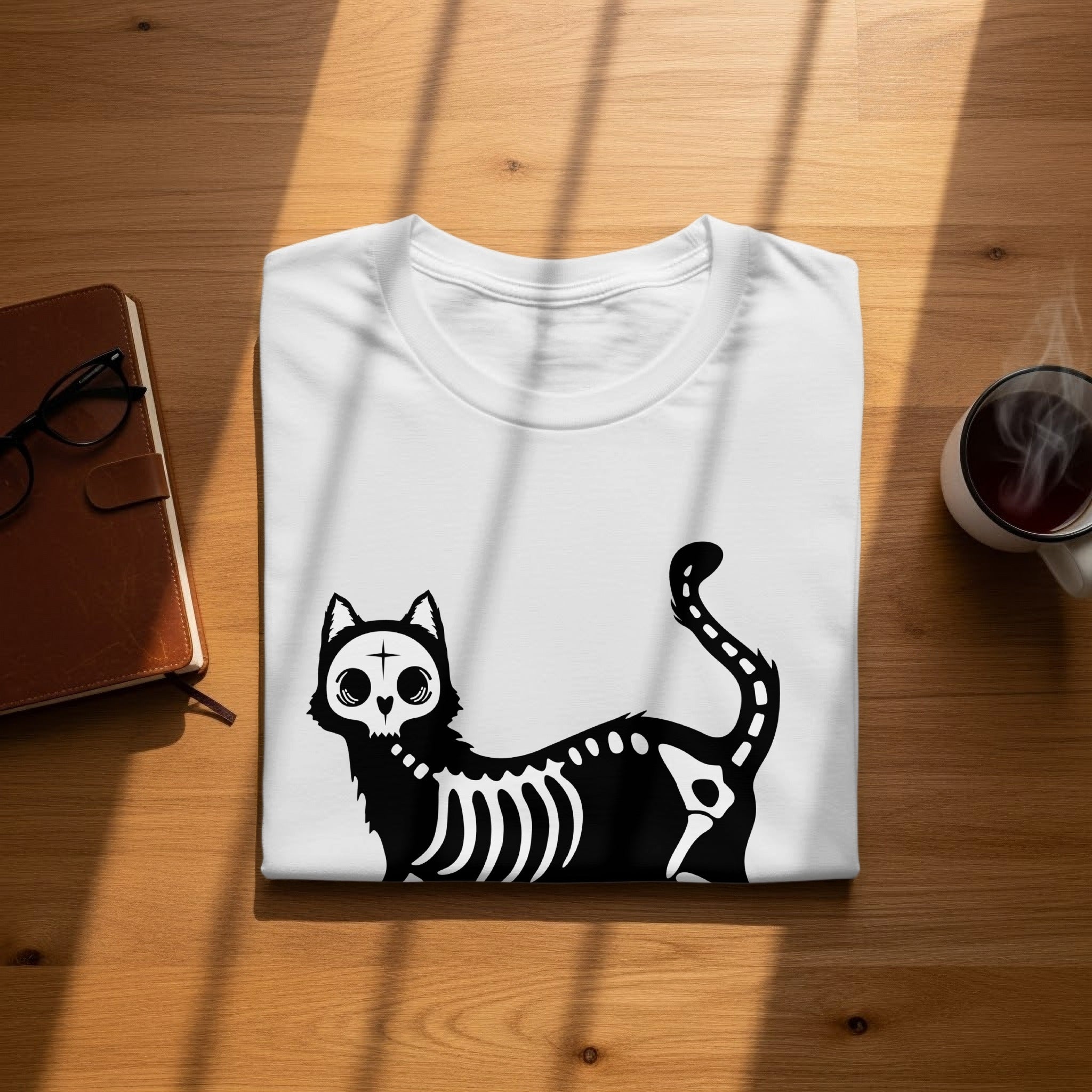 White t-shirt with black skeleton cat graphic on wooden surface.