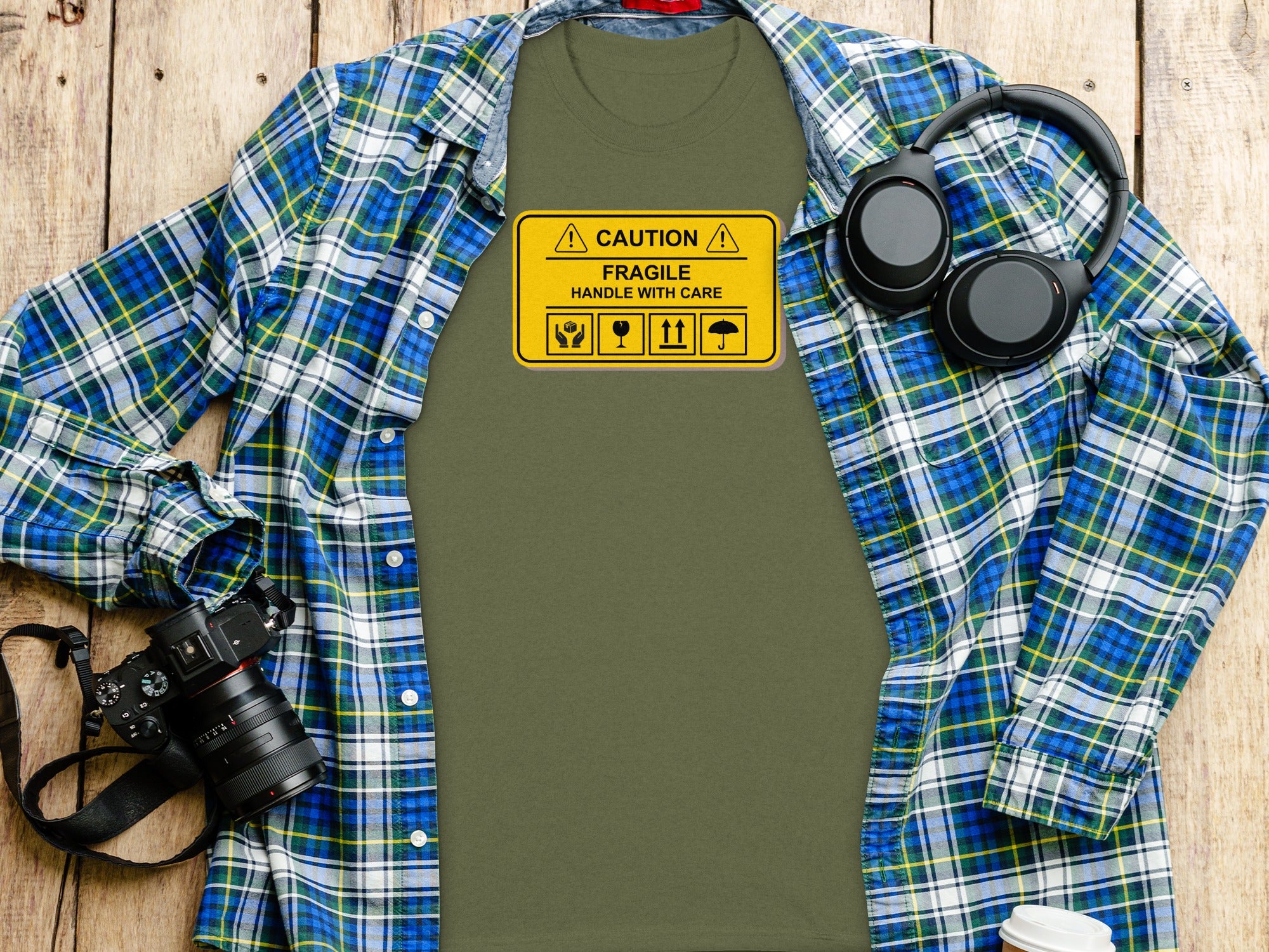 Olive green t-shirt with caution fragile handle with care warning label.