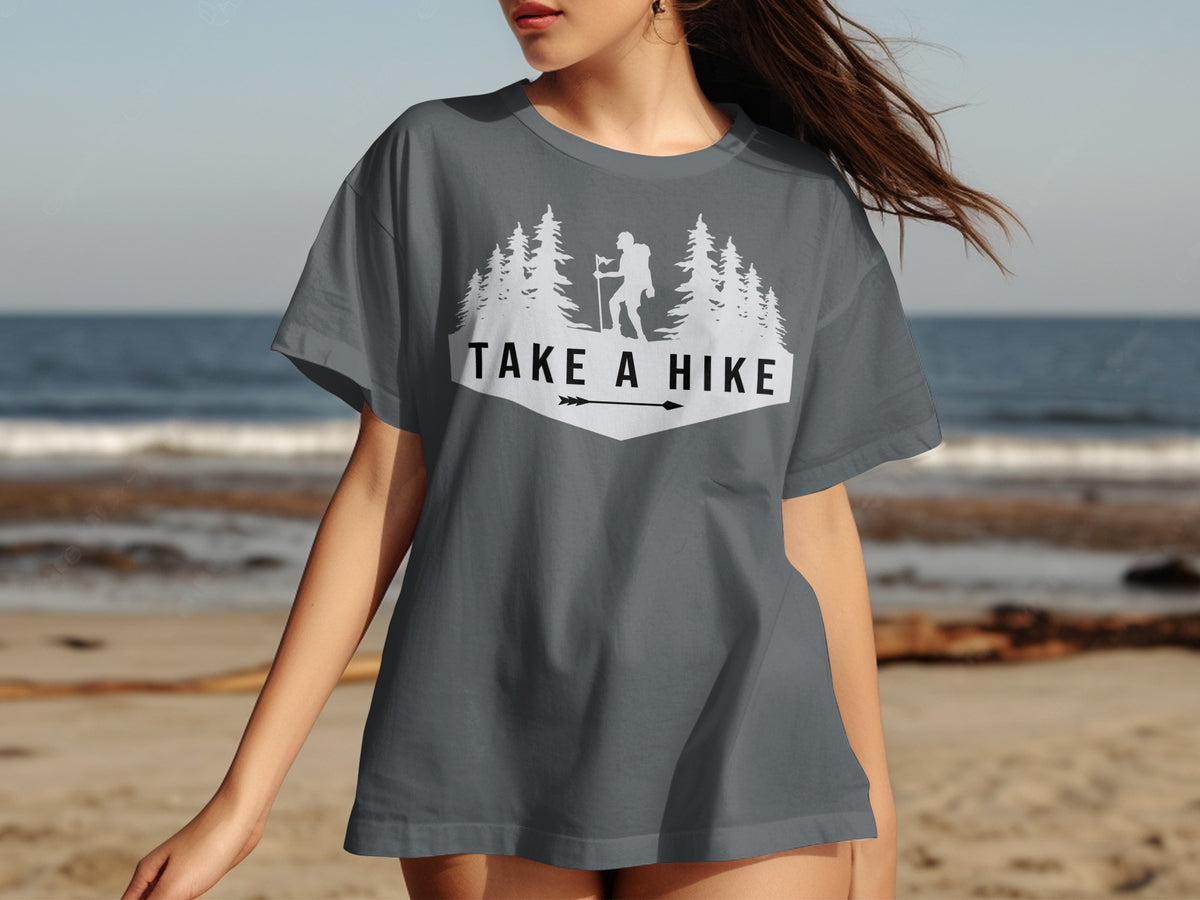 Grey t-shirt with white "Take A Hike" text, hiker silhouette, trees, and arrow.