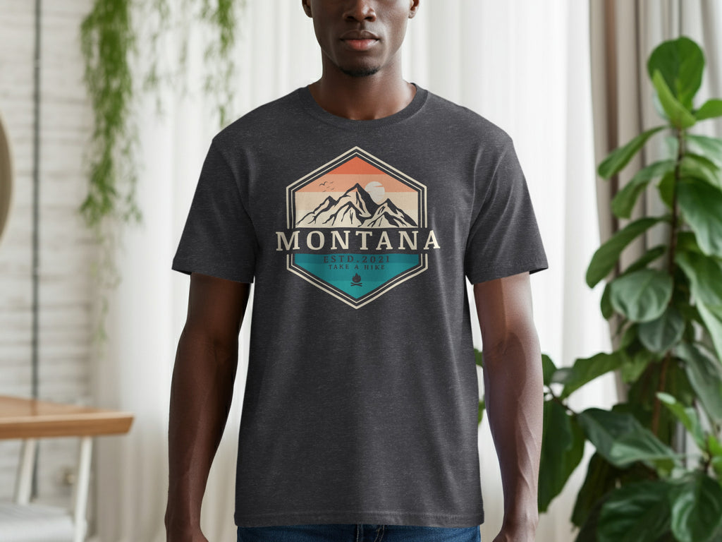 Dark t-shirt with a hexagonal graphic featuring mountains, sun, and "Montana Estd. 2021 Take a Hike."