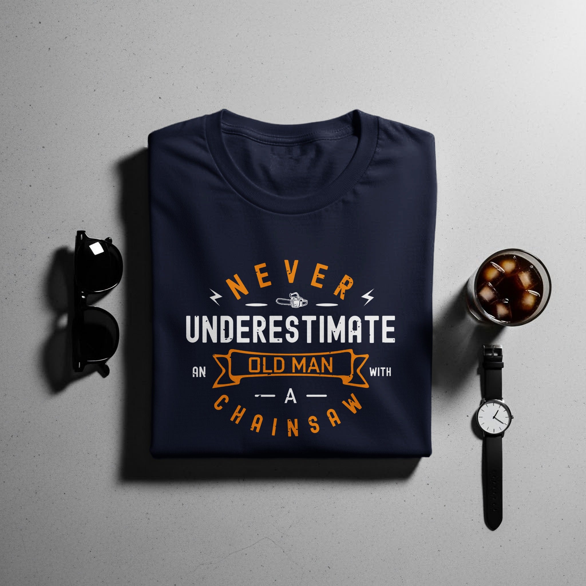 Dark blue t-shirt with "Never Underestimate an Old Man with a Chainsaw" graphic.