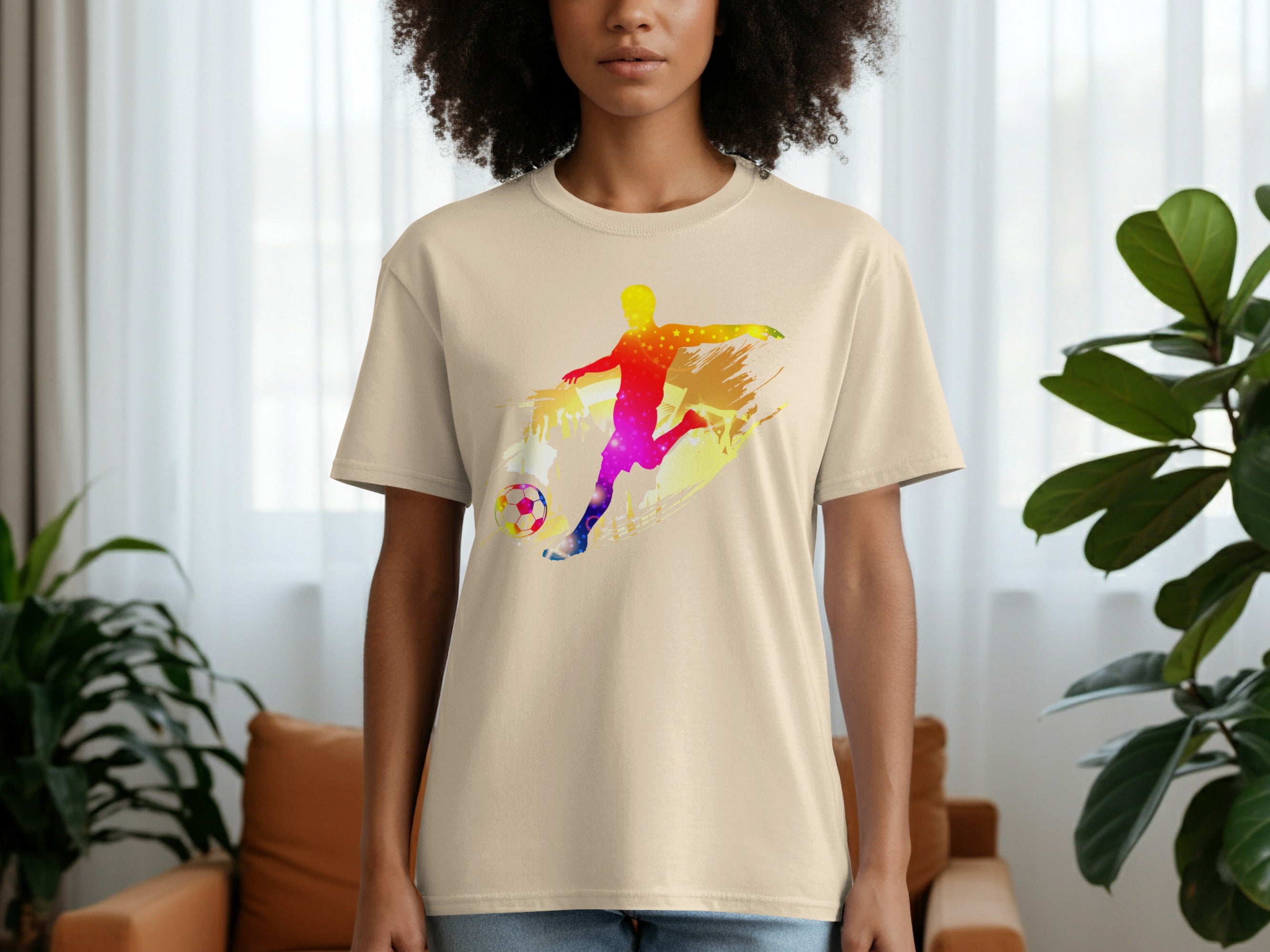 Cream t-shirt with a colorful, starry silhouette of a soccer player kicking a ball.