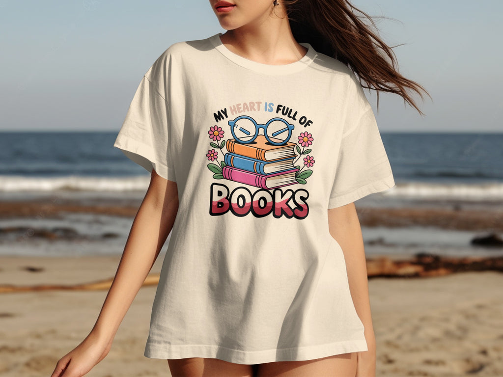 Cream t-shirt with a graphic of stacked books, glasses, flowers, and text "My Heart Is Full Of Books".