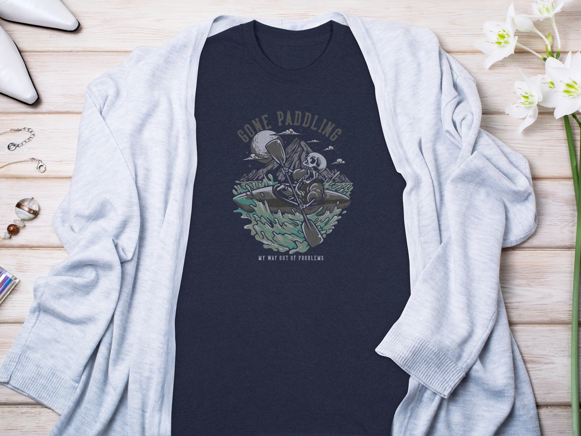 Dark blue t-shirt with graphic of skeleton kayaking and text "GONE PADDLING".