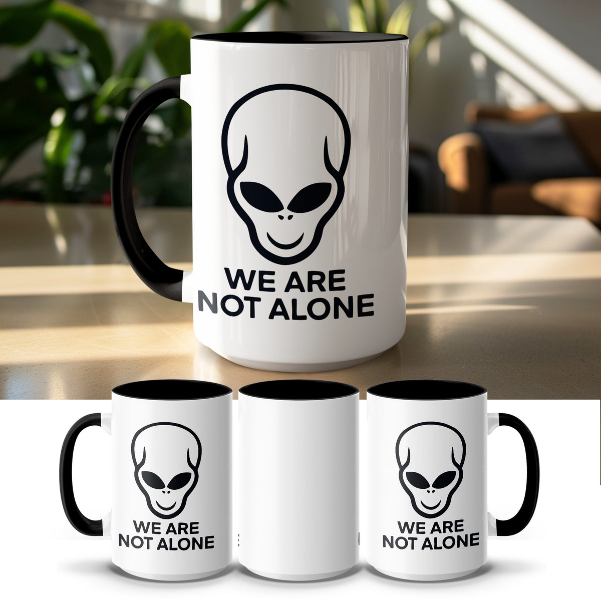 White mug with black interior, featuring a black alien head and "WE ARE NOT ALONE" text.