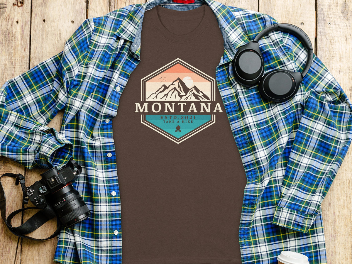 Brown t-shirt with "MONTANA ESTD. 2021 TAKE A HIKE" graphic and mountain scene.