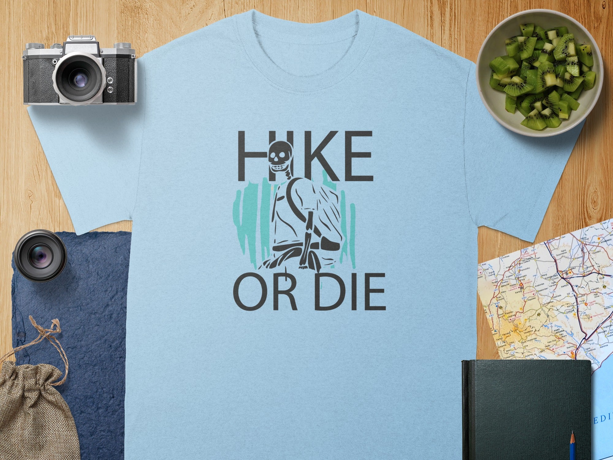 Light blue t-shirt with "HIKE OR DIE" text and skeleton hiker graphic.