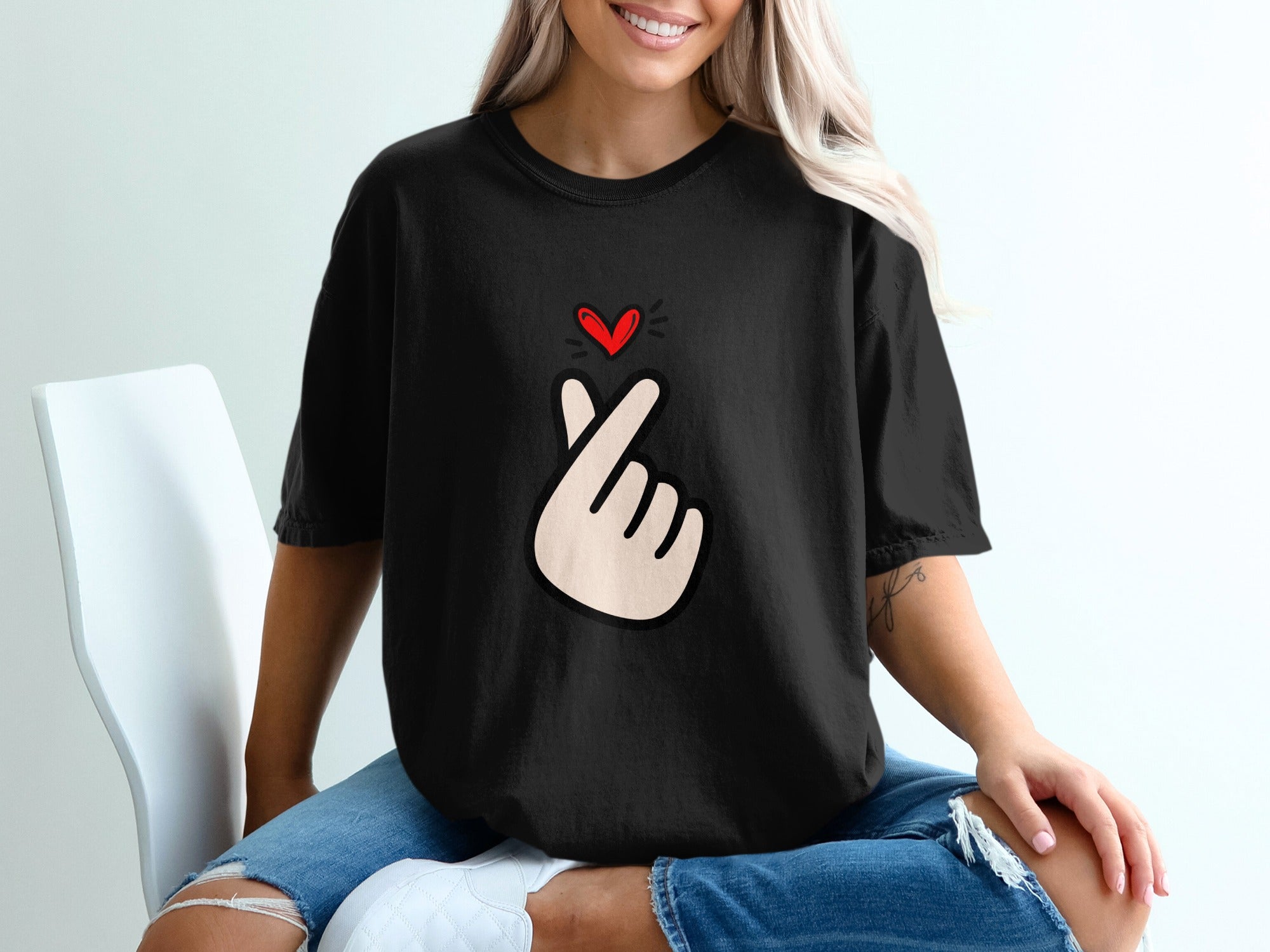Black t-shirt with a red heart and finger heart graphic on the chest.