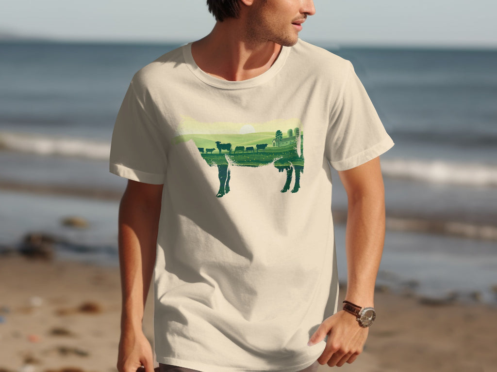 T-shirt with a dark green silhouette of a cow filled with a farm landscape.