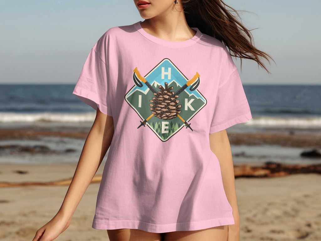Pink t-shirt with a graphic featuring a pinecone, crossed hiking poles, and the letters "HIK E".