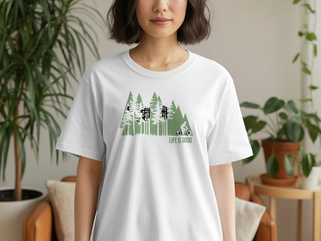 White t-shirt with green forest and cyclist graphic, text "LIFE IS GOOD".