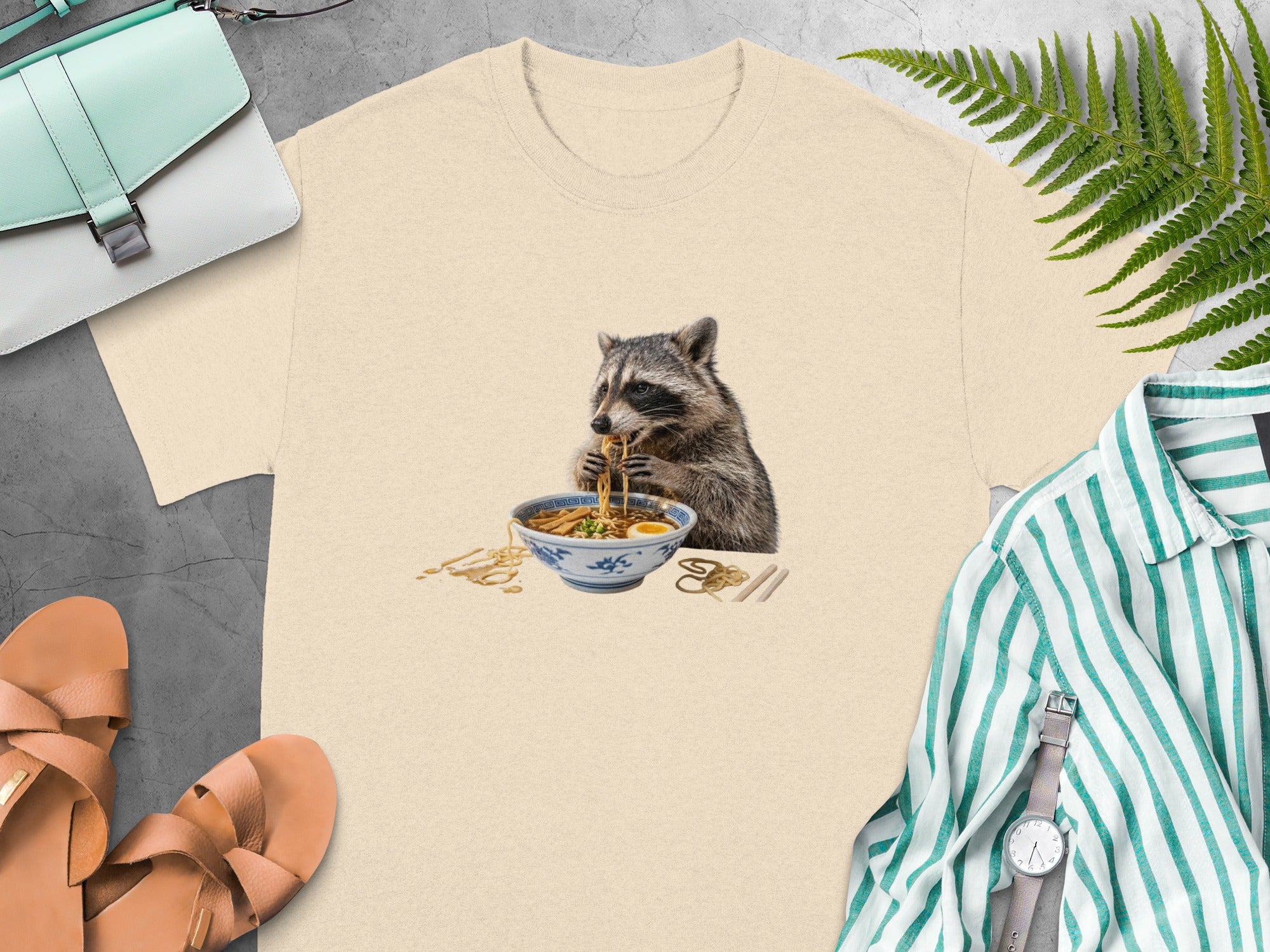 T-shirt with raccoon eating ramen noodles design.