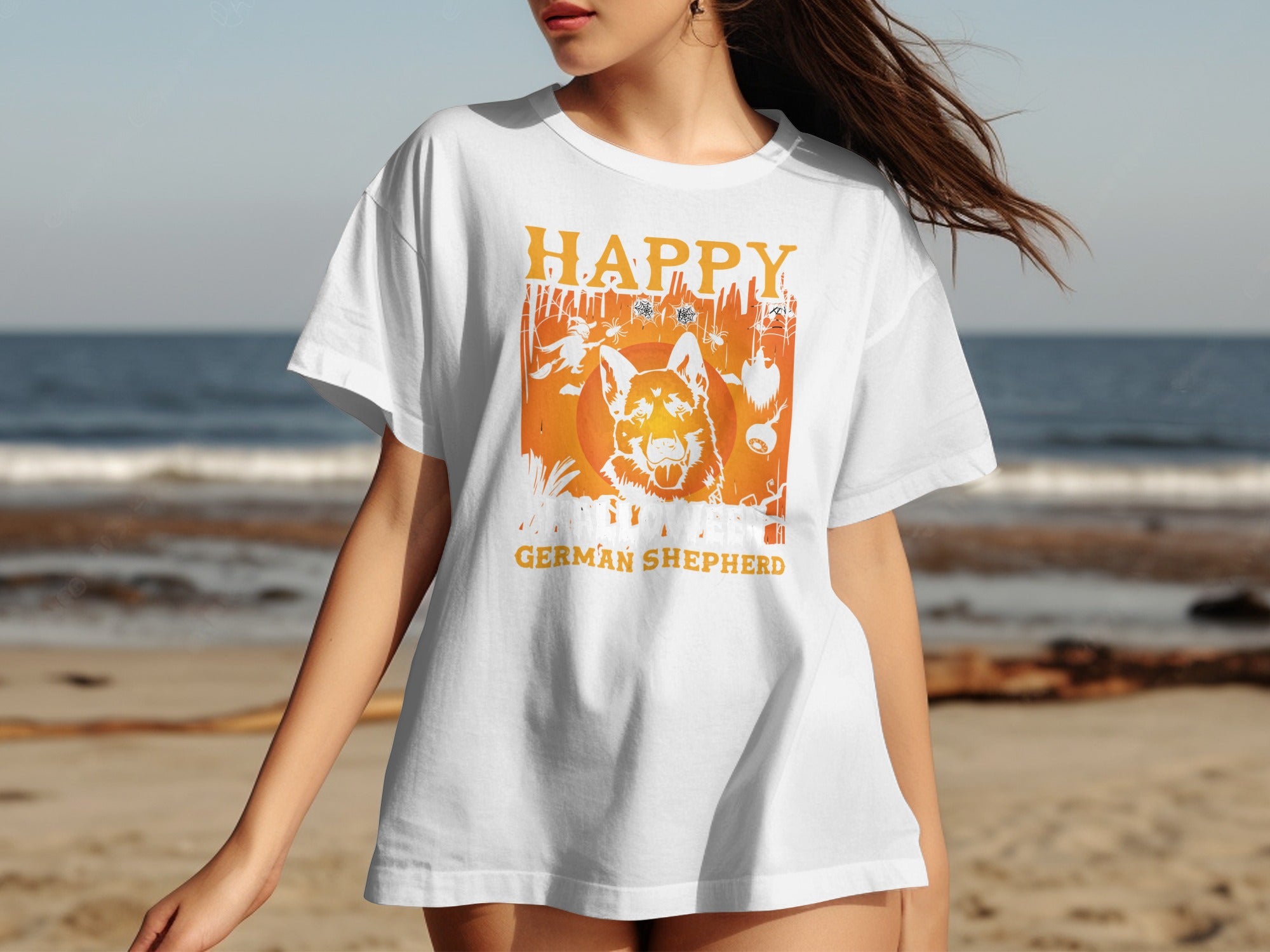 White t-shirt with "Happy German Shepherd" Halloween graphic on a beach.