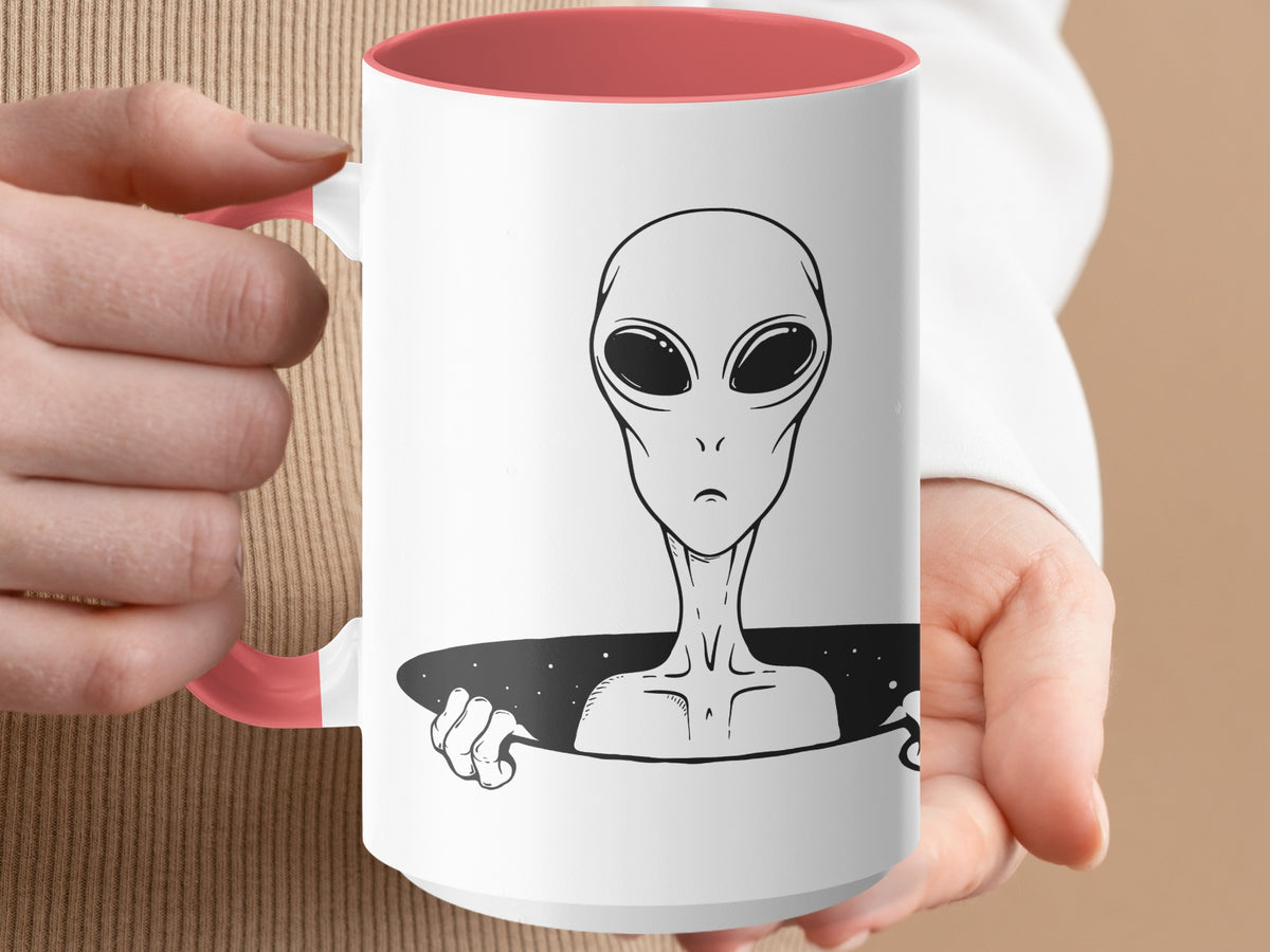 White mug with coral handle features a black and white alien illustration.