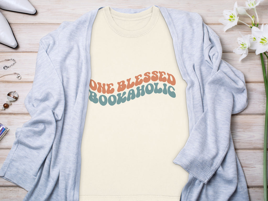 Cream t-shirt with retro "One Blessed Bookaholi" text in coral and teal.