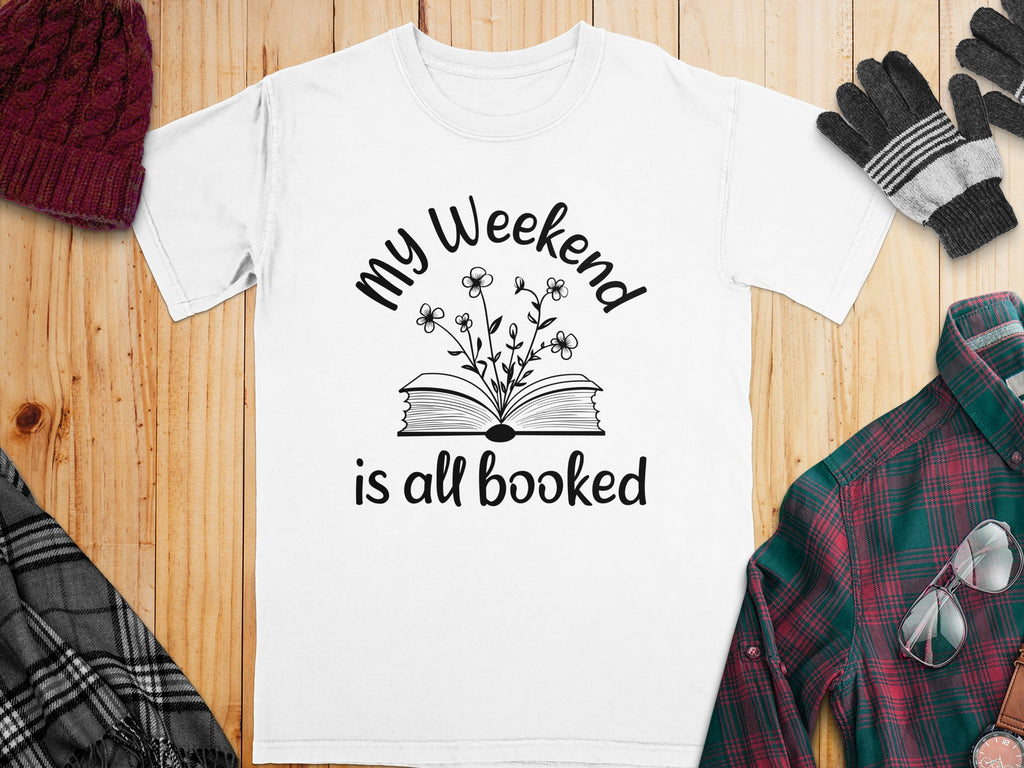 White t-shirt with black text: "my Weekend is all booked" and floral book graphic.