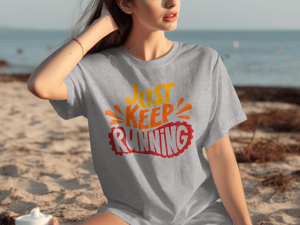 Gray t-shirt with "Just Keep Running" text in orange and red on a beach.