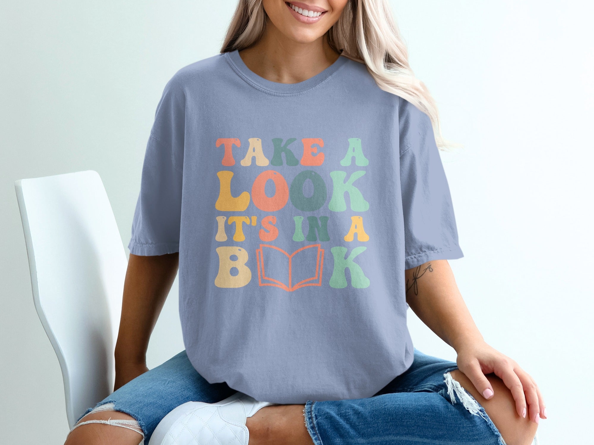 T-shirt with text "TAKE A LOOK IT'S IN A BOOK" and book graphic.