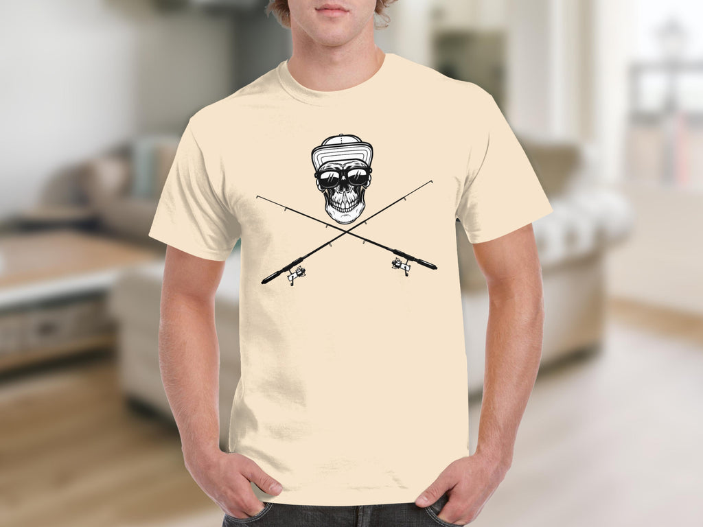 Skull wearing sunglasses and hat with crossed fishing rods graphic on tan t-shirt.