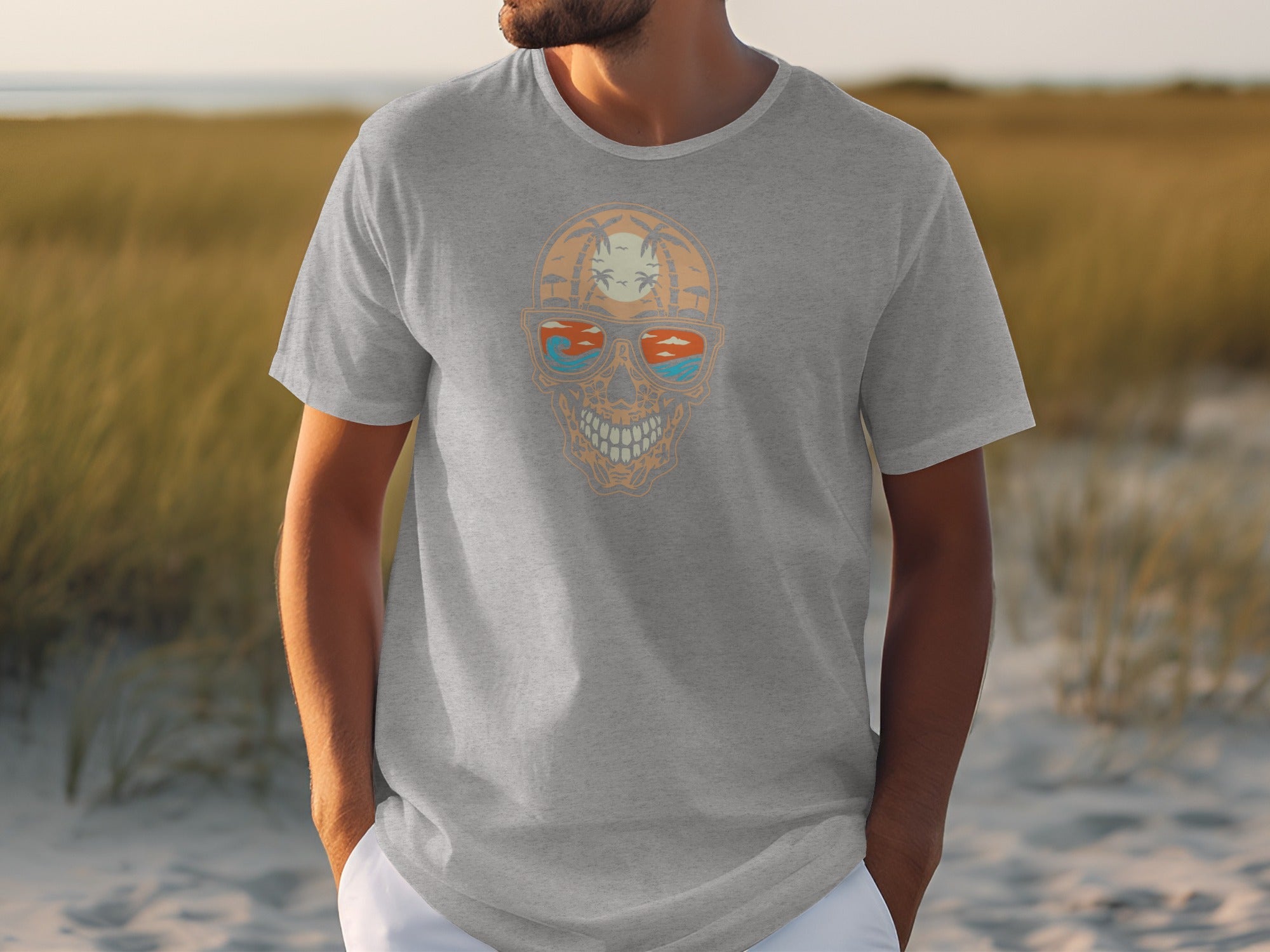 Grey t-shirt with a skull graphic featuring a tropical sunset reflected in sunglasses.