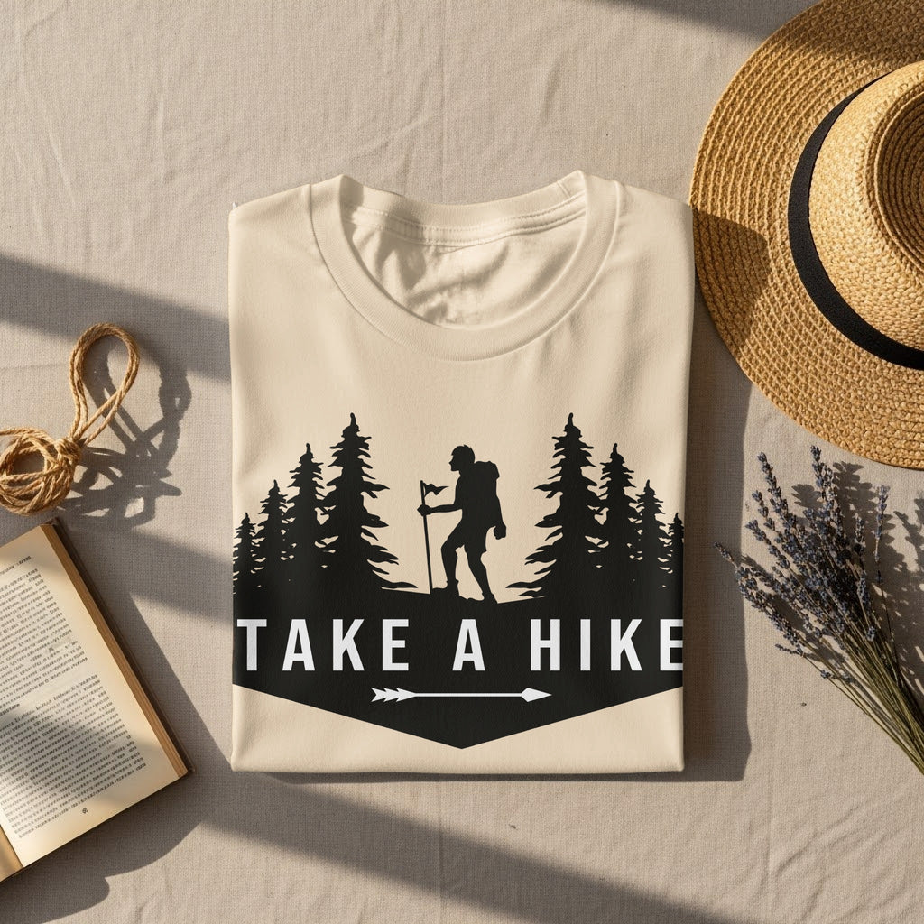Cream t-shirt with black graphic of hiker, trees, and text "TAKE A HIKE".