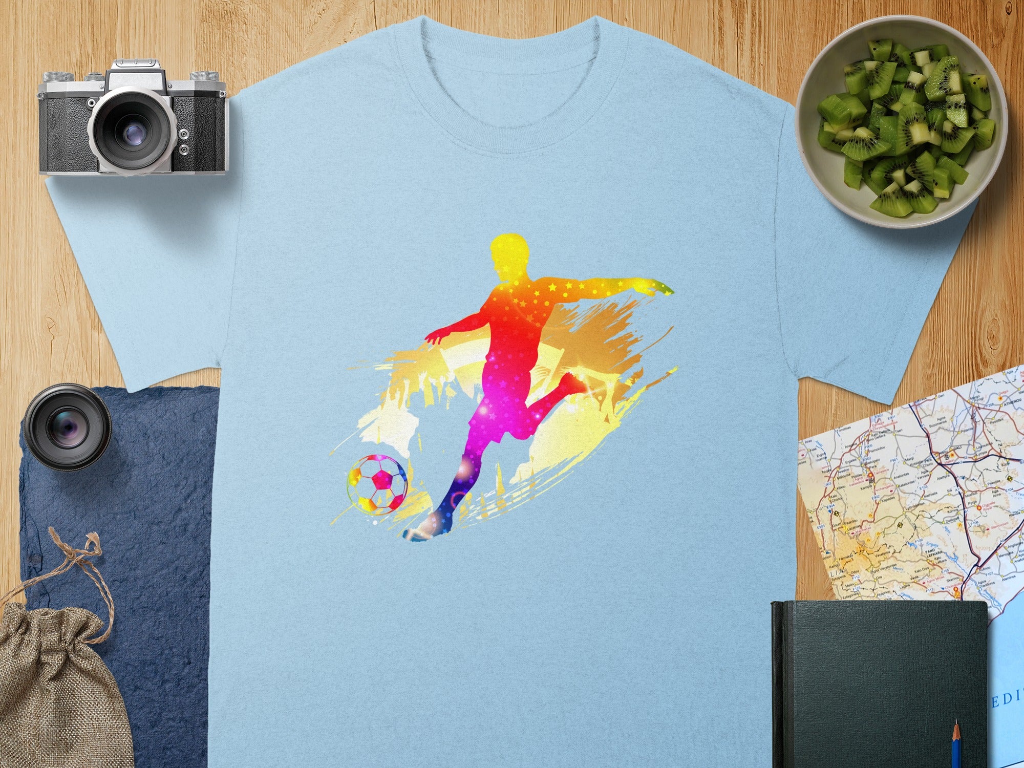 Light blue t-shirt with colorful soccer player graphic and soccer ball design.