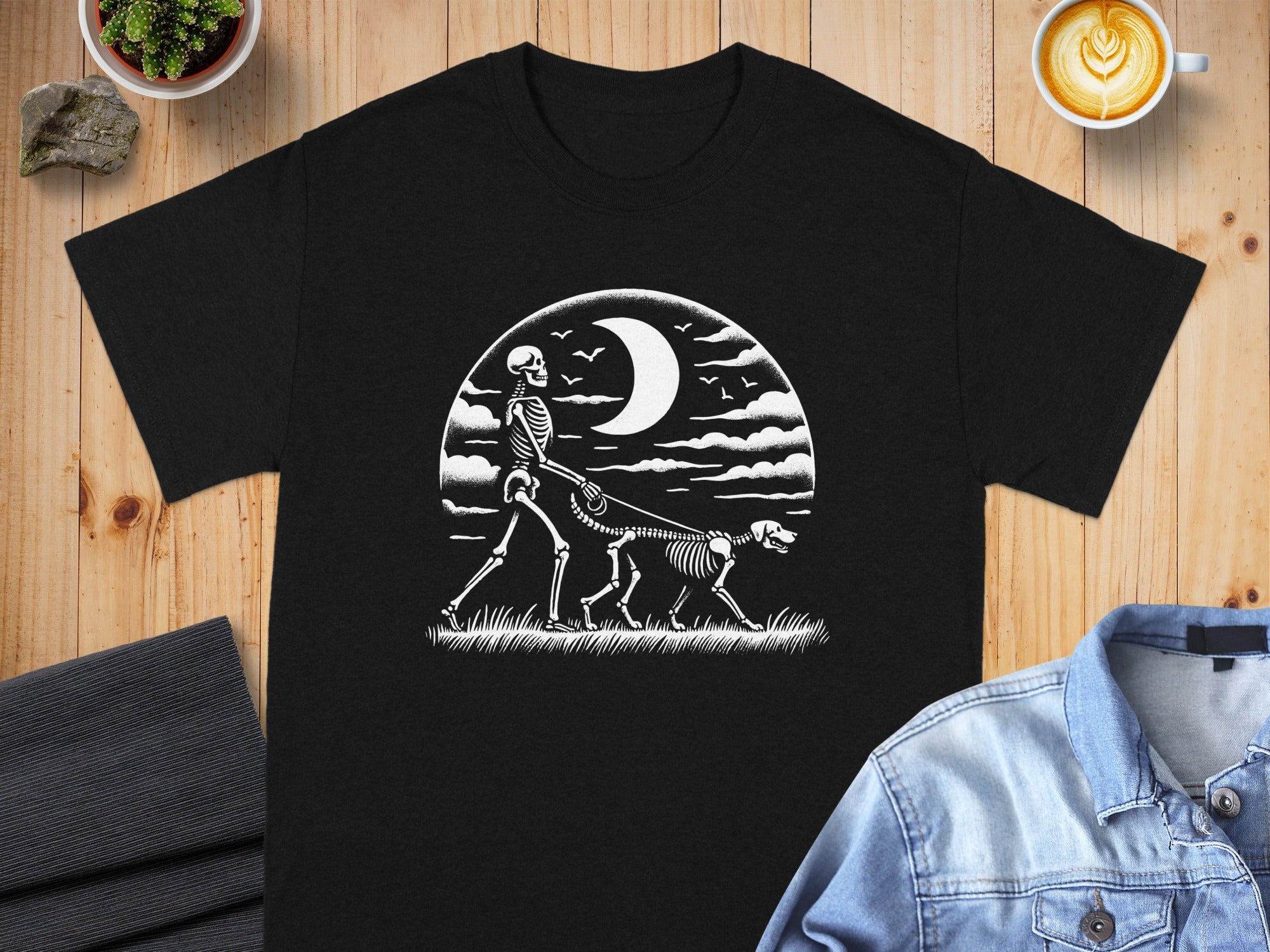 Black t-shirt with a white graphic of a skeleton walking a dog under a crescent moon.