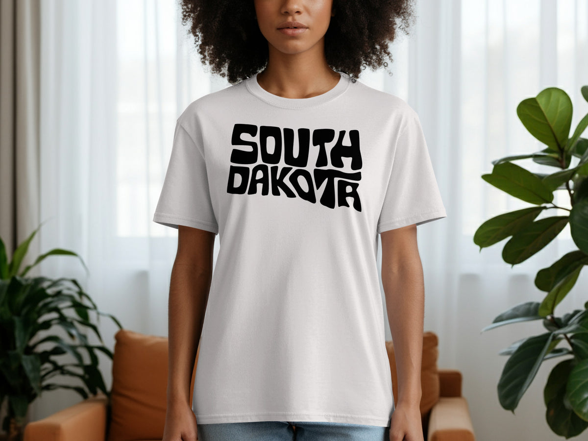 White t-shirt on a person with "SOUTH DAKOTA" in black stylized text.