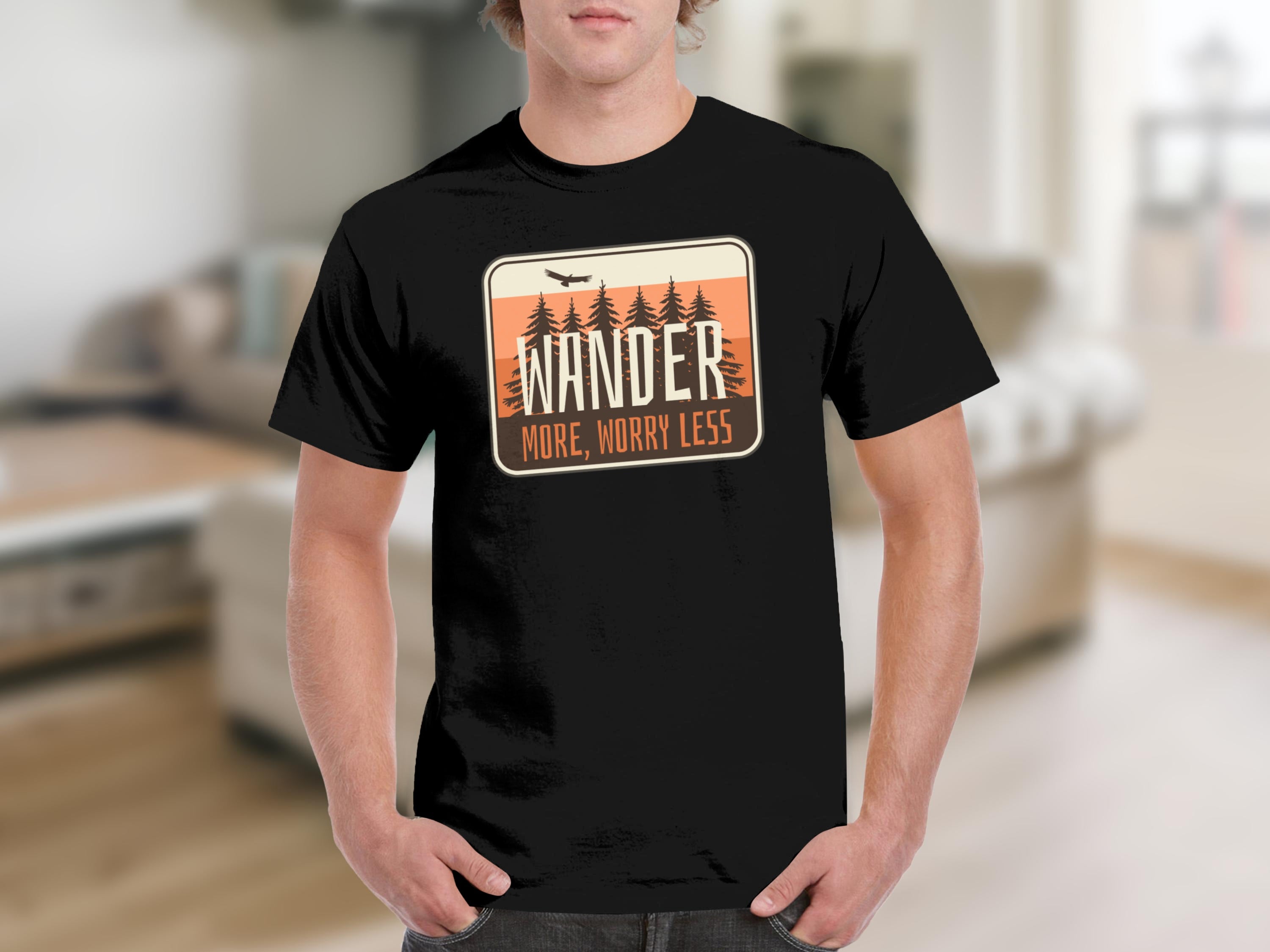 Black t-shirt with a graphic featuring pine trees, a bird, and the text "WANDER MORE, WORRY LESS".