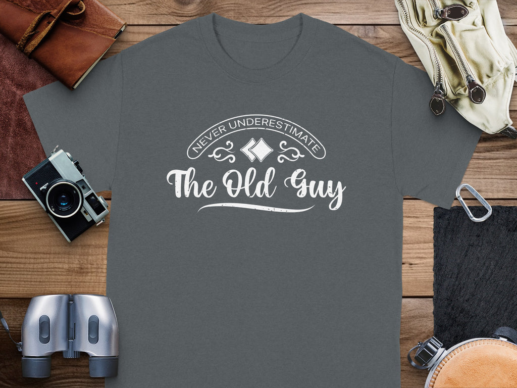 Dark gray t-shirt with white text "Never Underestimate The Old Guy".