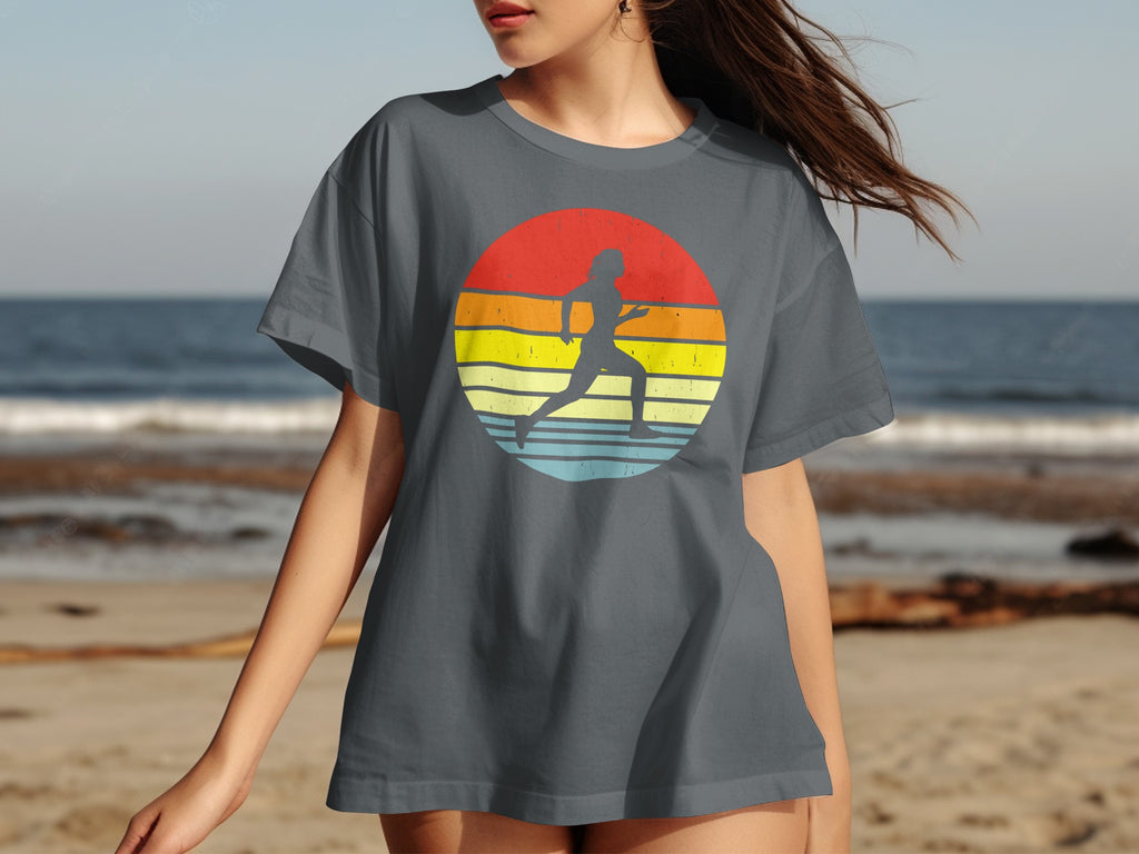 Dark grey t-shirt with a runner silhouette against a retro striped circle at the beach.