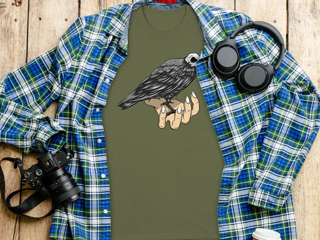 Green t-shirt with a crow skull graphic on a hand.