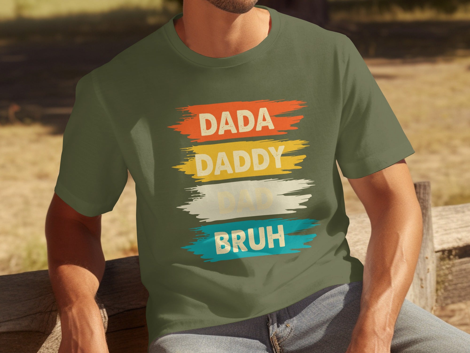 Green t-shirt with "DADA," "DADDY," "DAD," and "BRUH" text in colored brush strokes.