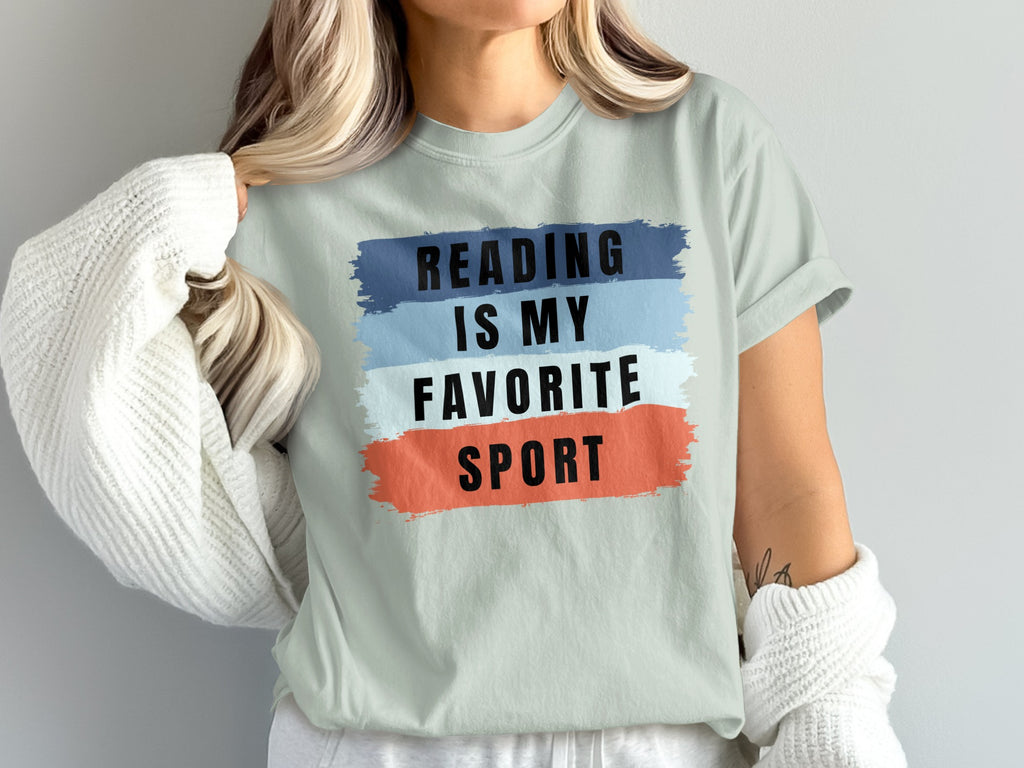 Mint t-shirt with black text "READING IS MY FAVORITE SPORT" on colored brush strokes.
