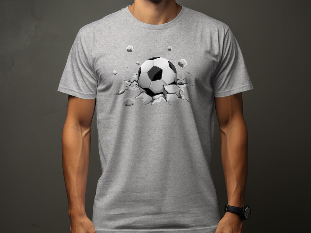 Grey t-shirt with a realistic soccer ball bursting through cracked concrete design.