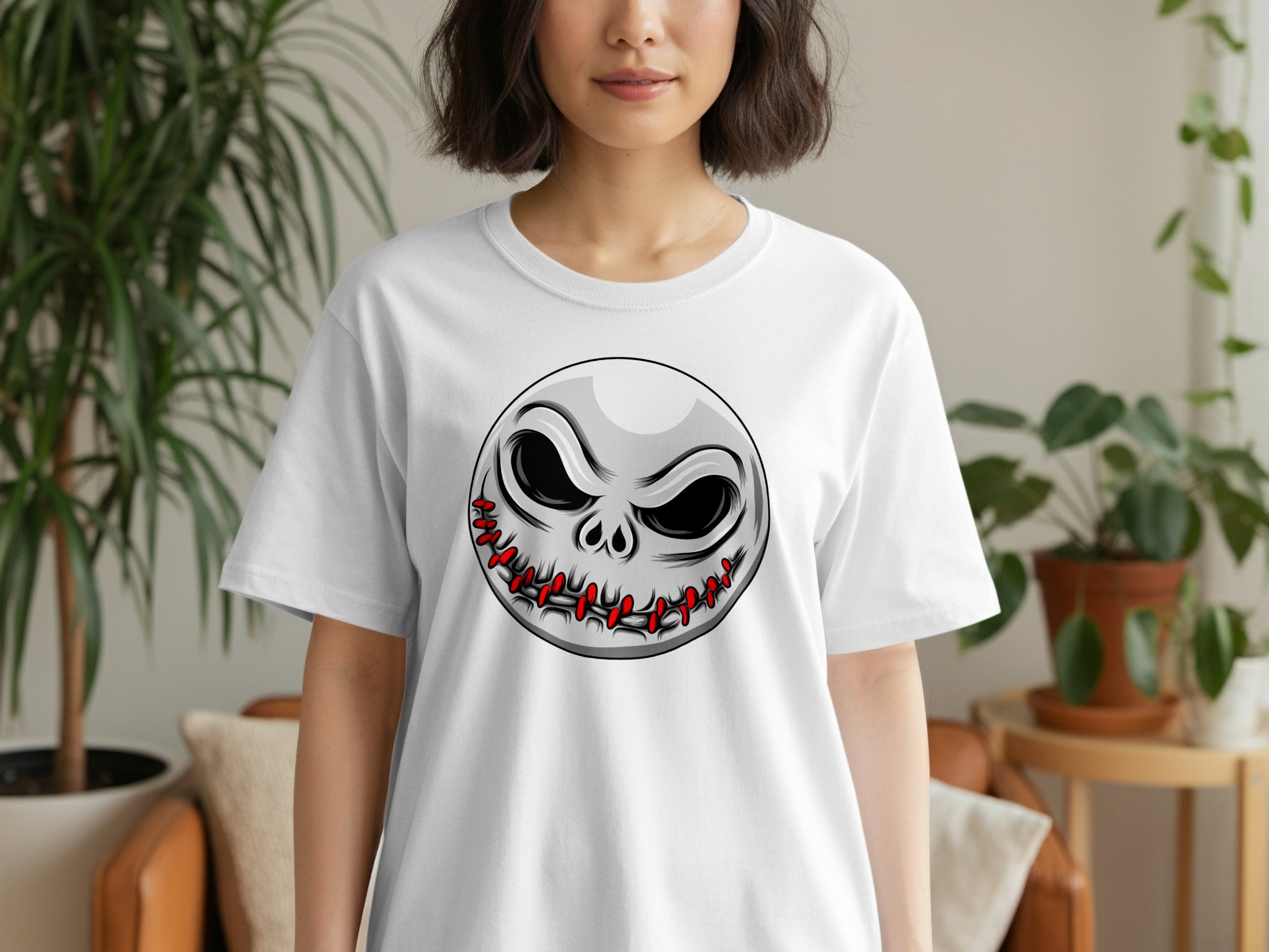 White t-shirt with a grey, spooky grinning skull graphic stitched with red thread.