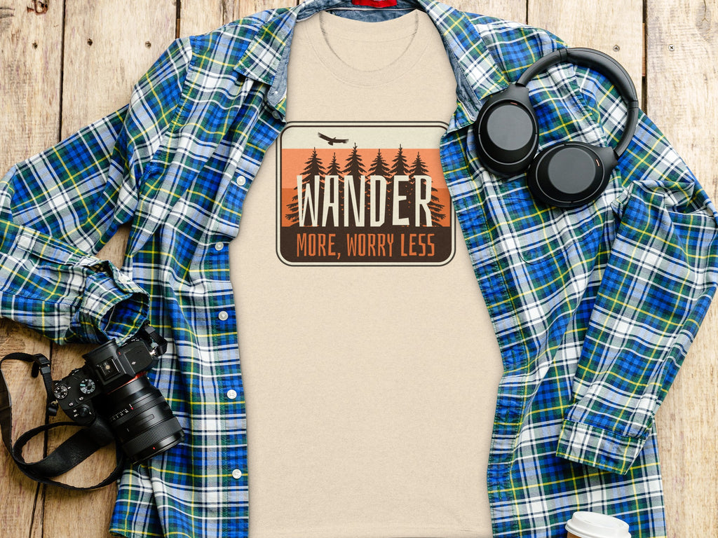 Beige t-shirt with "Wander More, Worry Less" graphic and plaid shirt.