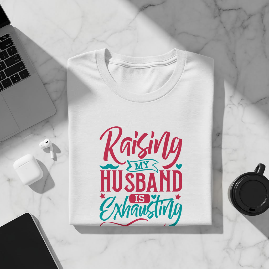 White t-shirt with "Raising my husband is exhausting" text in pink and teal.