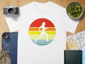 White t-shirt with a vintage runner graphic on a striped sunset background.