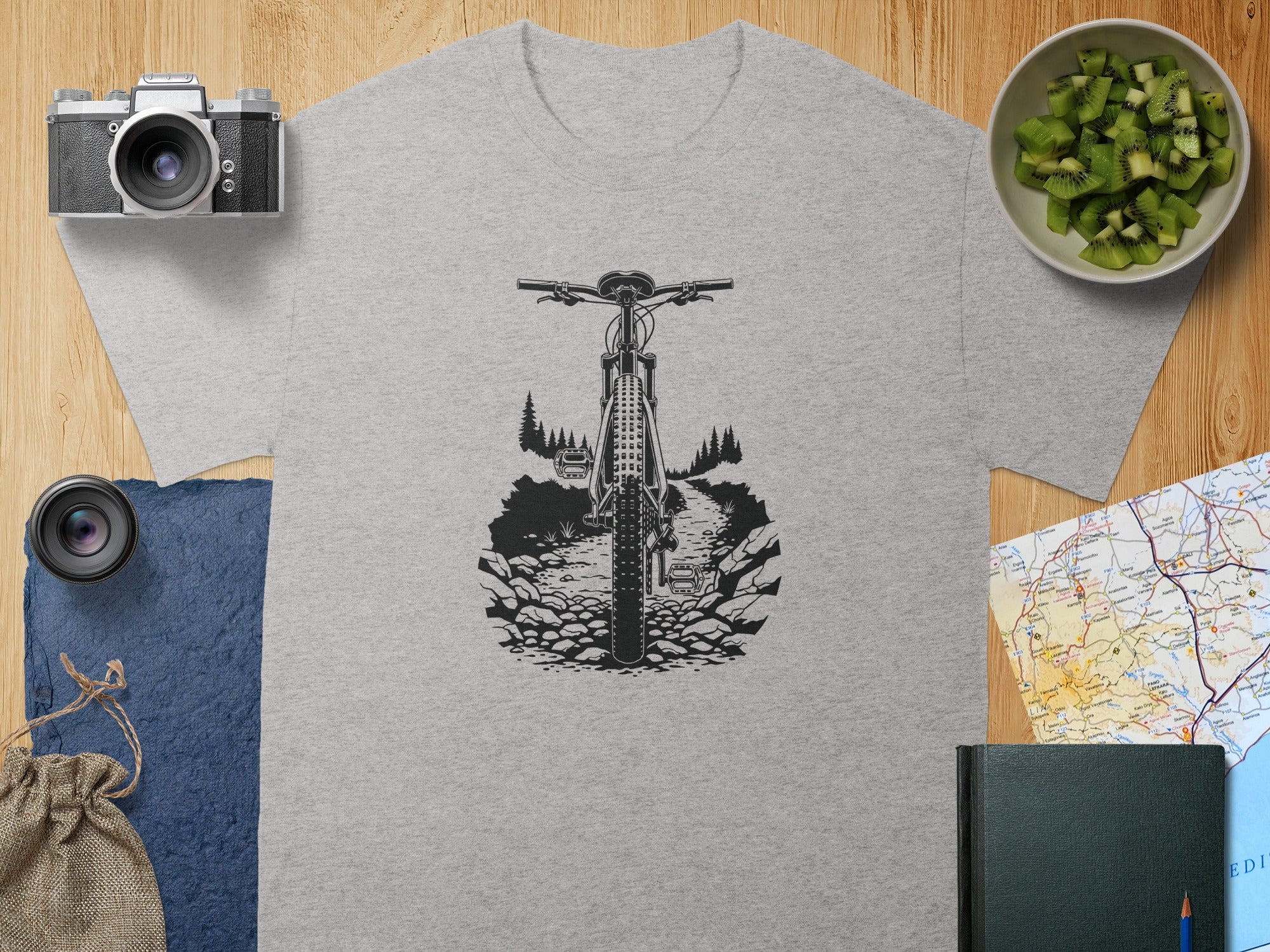 Grey t-shirt with a black mountain bike graphic on a rocky trail.